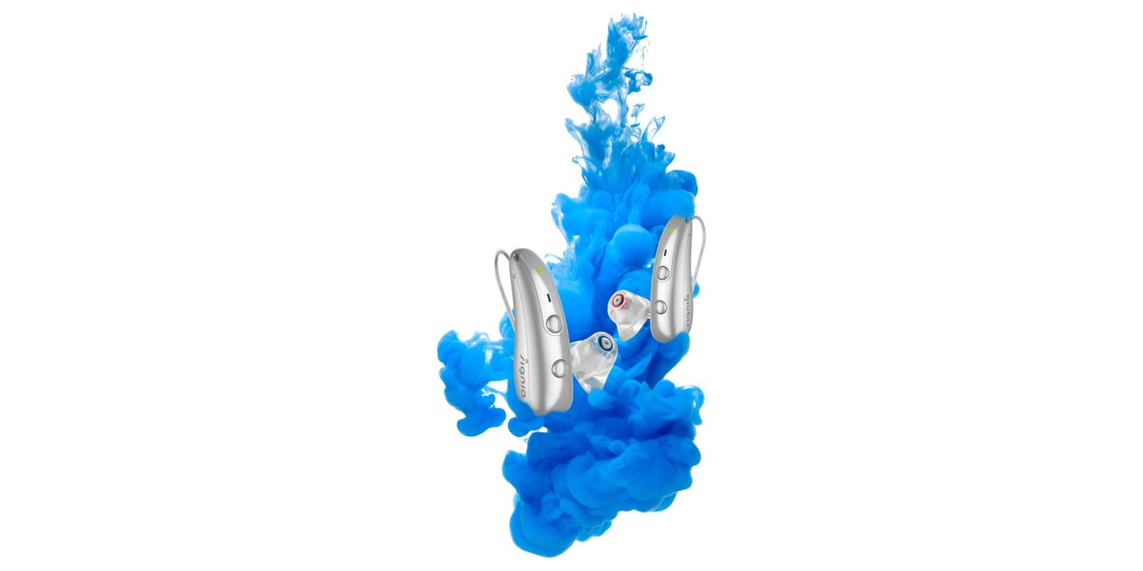 Zwei Hörgeräte mit Ohrpassstücken vor blauem Farbrauch auf Weiß